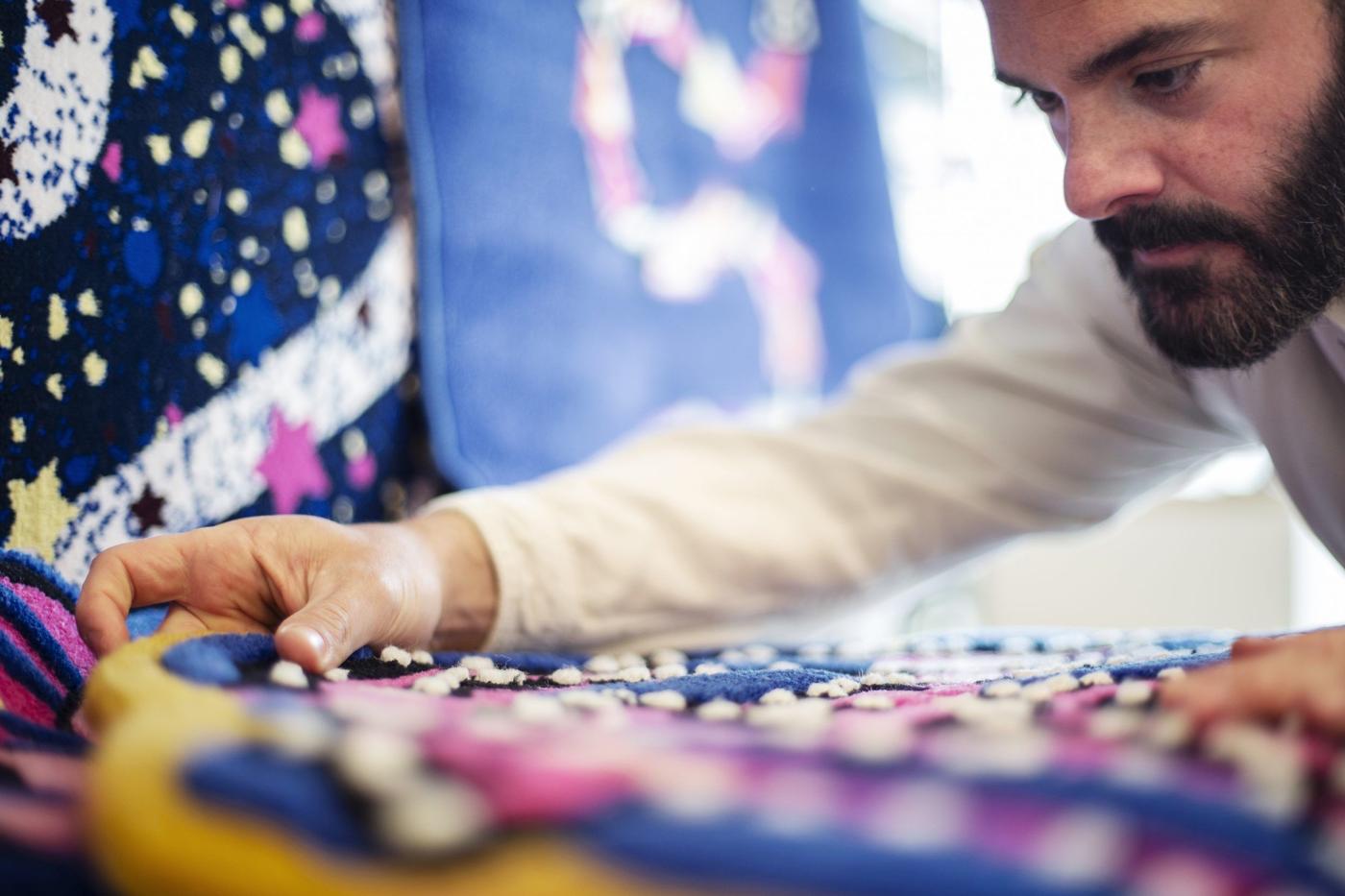 Luis Gomez Barquin studying one of his colourful rug designs closely.