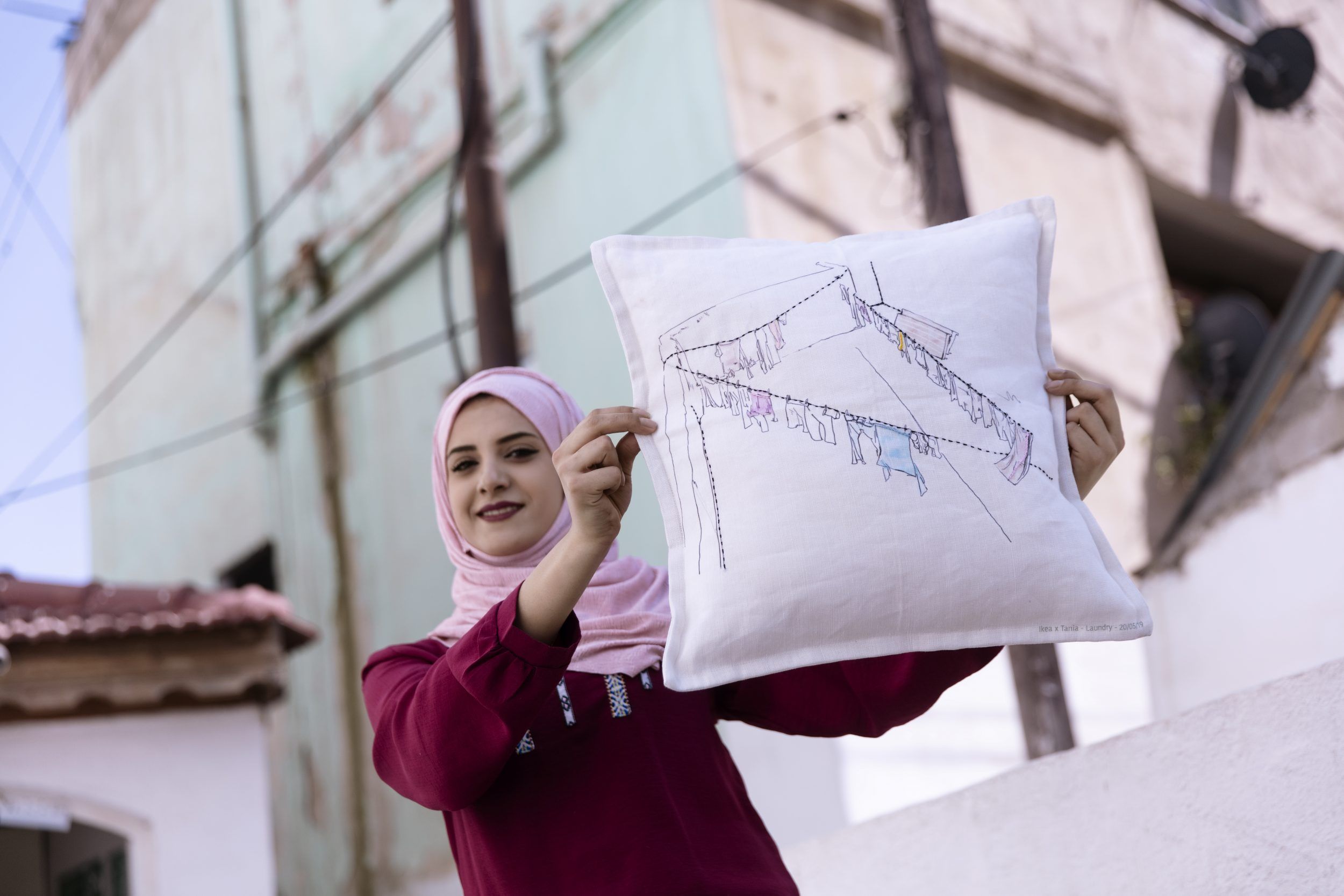 An artisan holding up a cushion with embroidery.