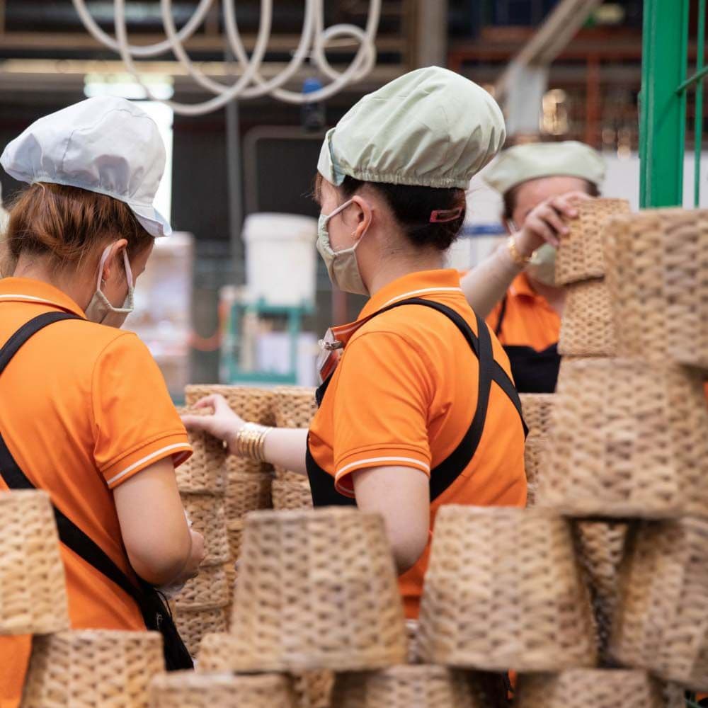 Three factory workers quality checking baskets in a factory.