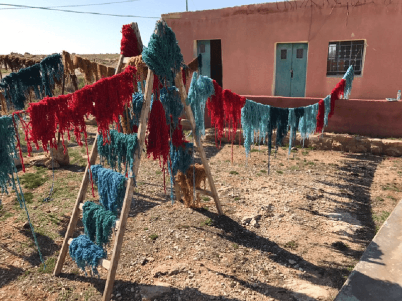 Blue and red yarns hang on washing lines to dry.