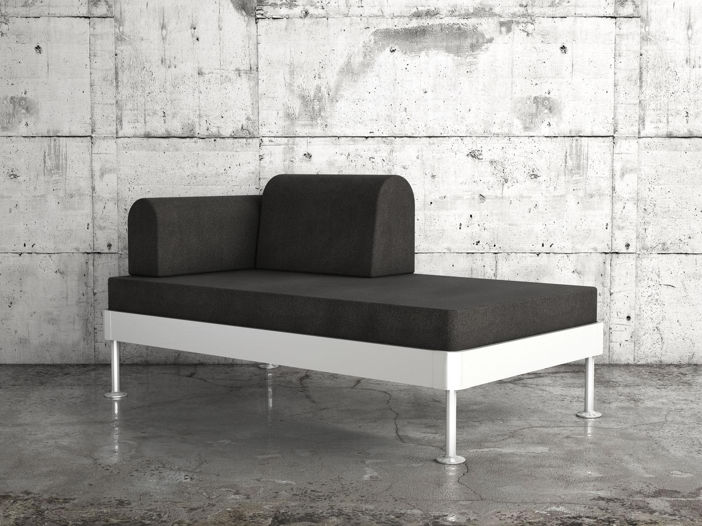 A grey chaise longue with a white base against a concrete background.