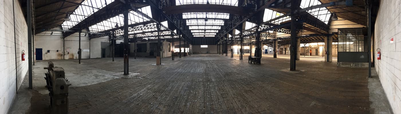 A wide angle photo of a large industrial event space, with plenty of windows.