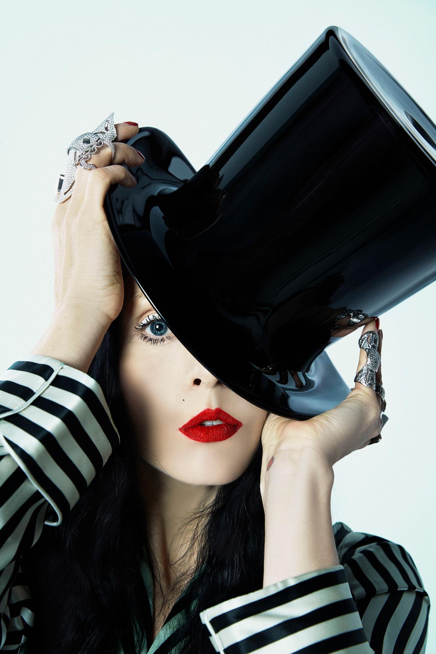 A woman wears a black top hat tipped over one eye.