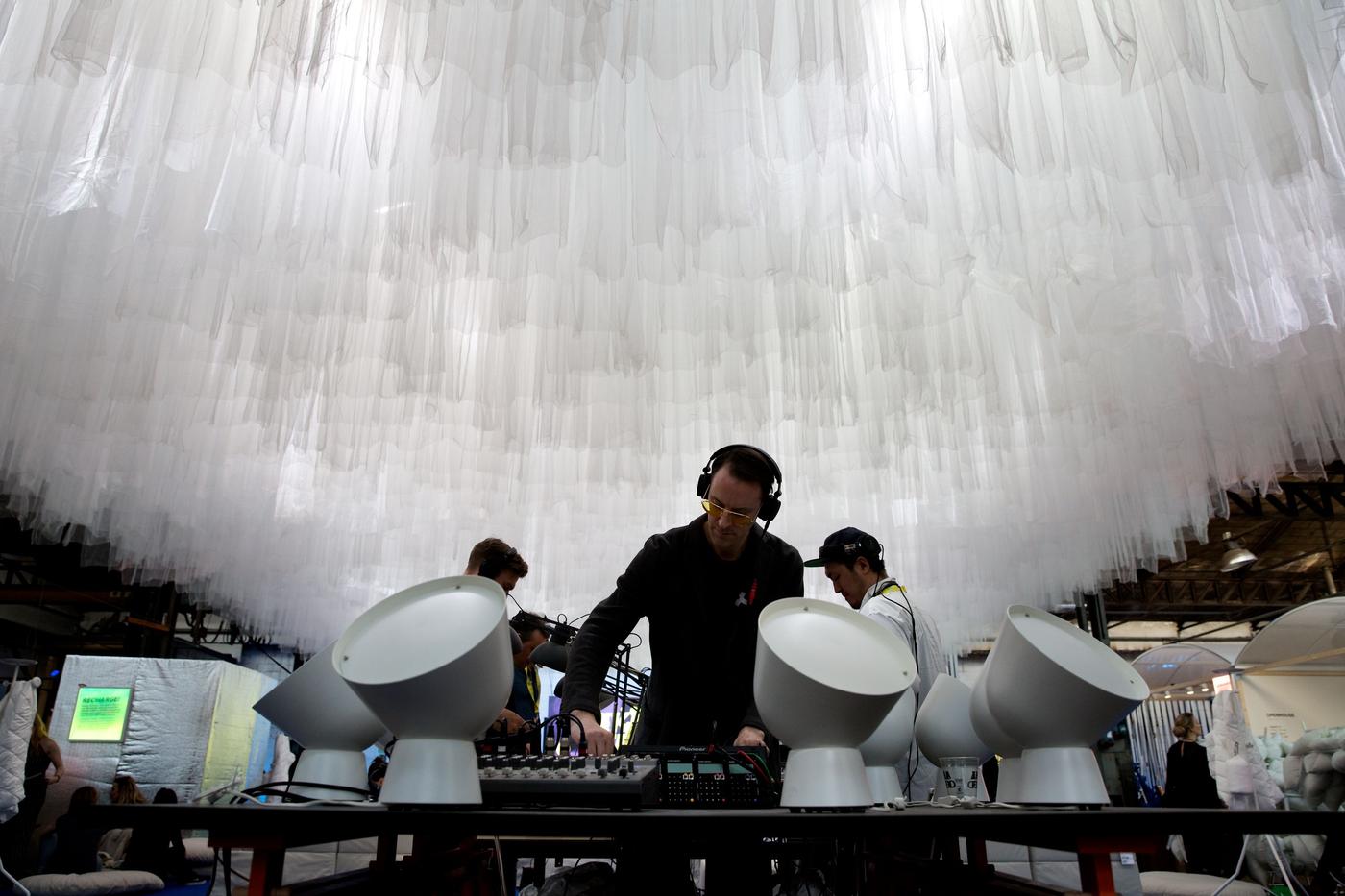 Three people are playing music. They are surrounded by giant lights.