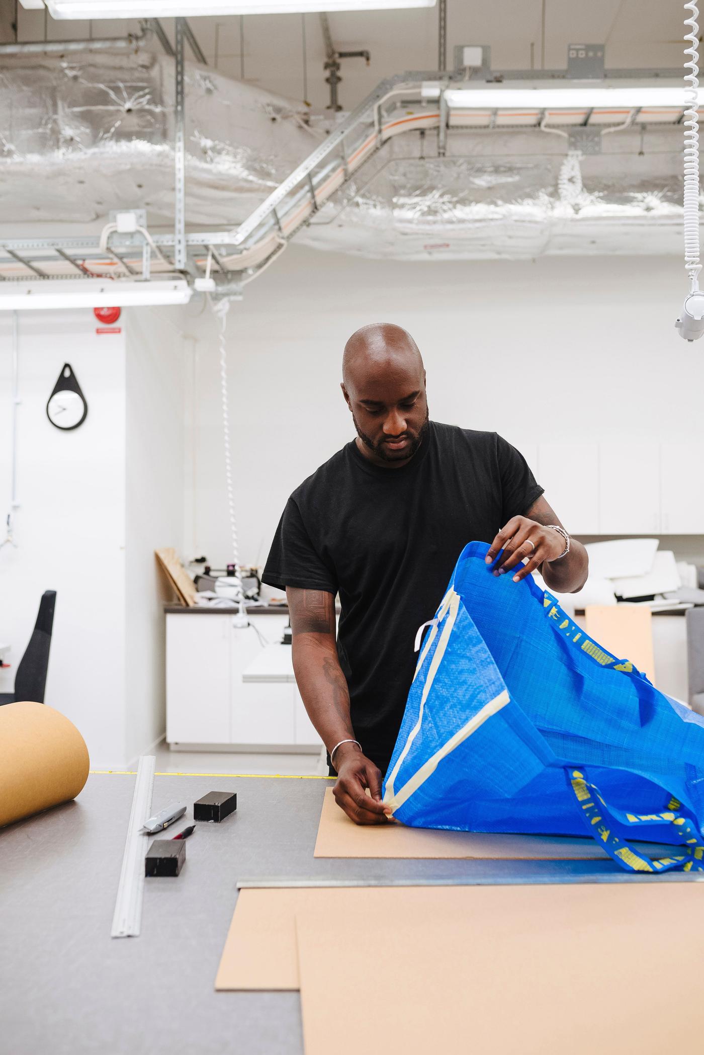 Virgil Abloh in a brightly-lit workshop examining a blue FRAKTA bag. 