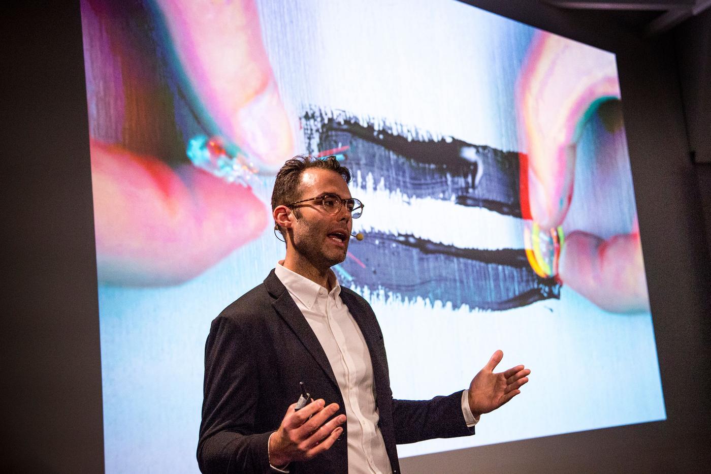 A person presents in front of visuals on a screen.