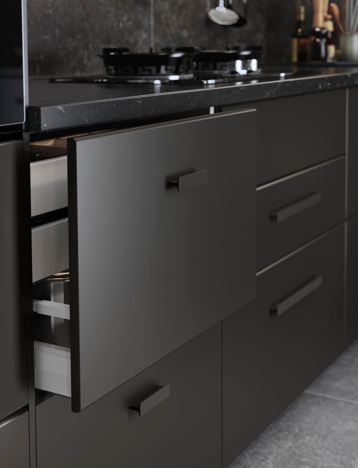 A black fronted kitchen drawer. The drawer is partly open.