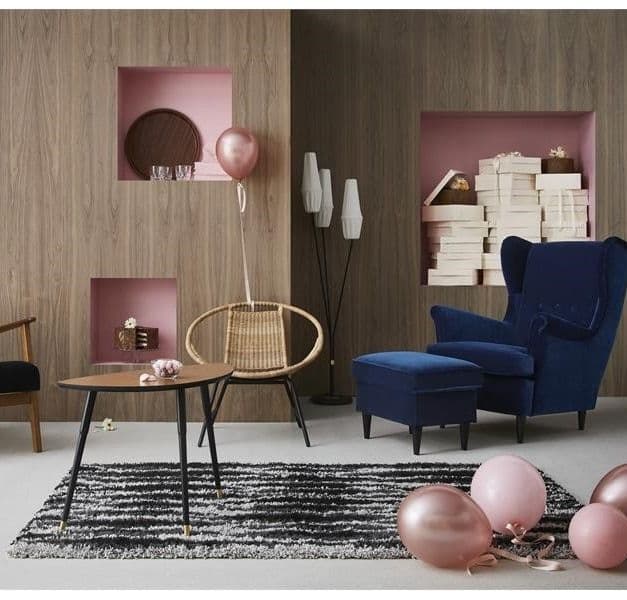 A living room with IKEA furniture and many pink balloons.