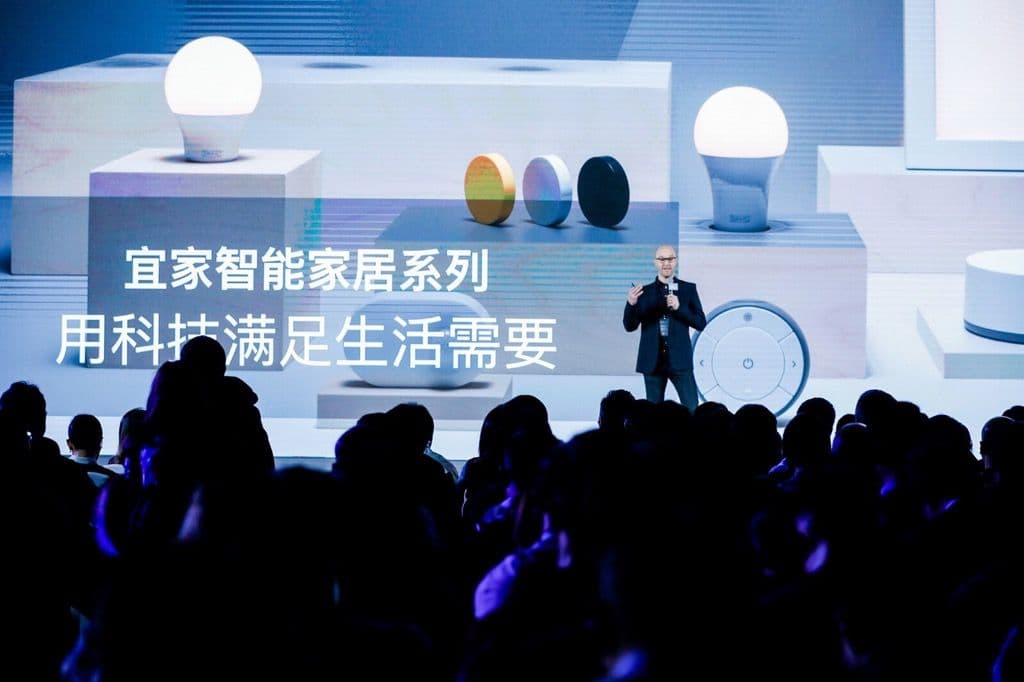 A person presents about smart light bulbs on a stage in front of a large audience.