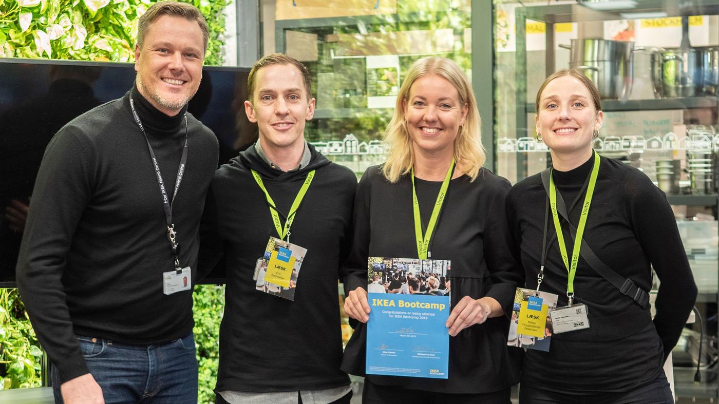Two men and two women smile at the camera. A woman is holding a certificate.