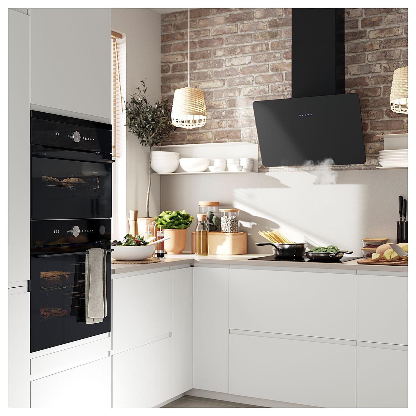 Corner of a white kitchen with raw brick walls.