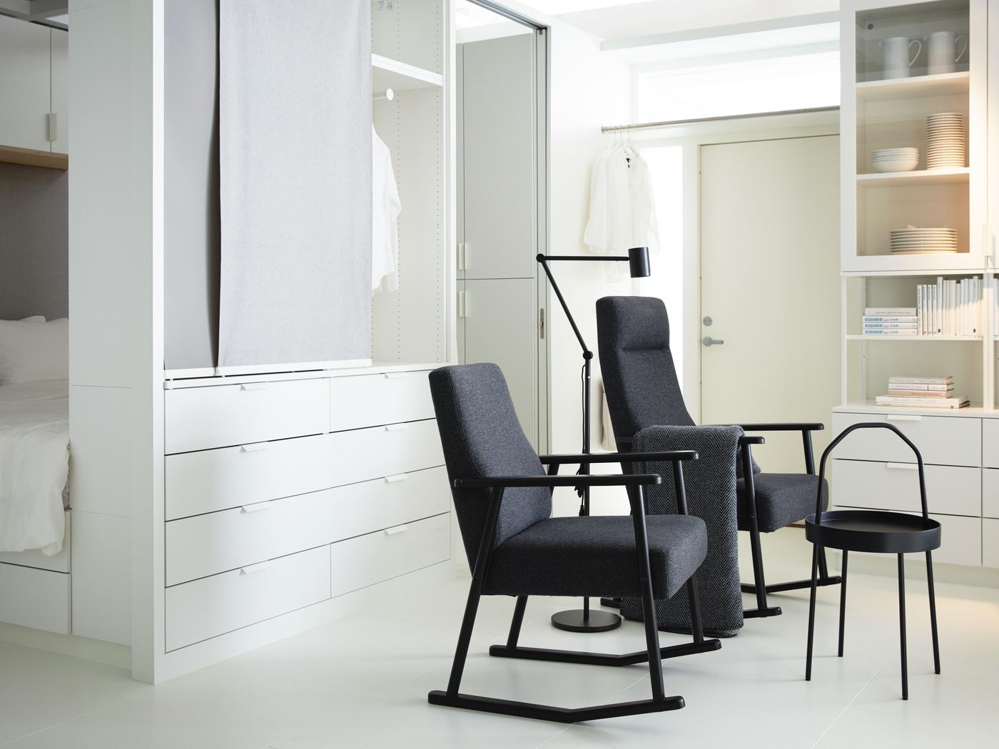 Bright, white room with two black armchairs, a black floor lamp and black side table. 