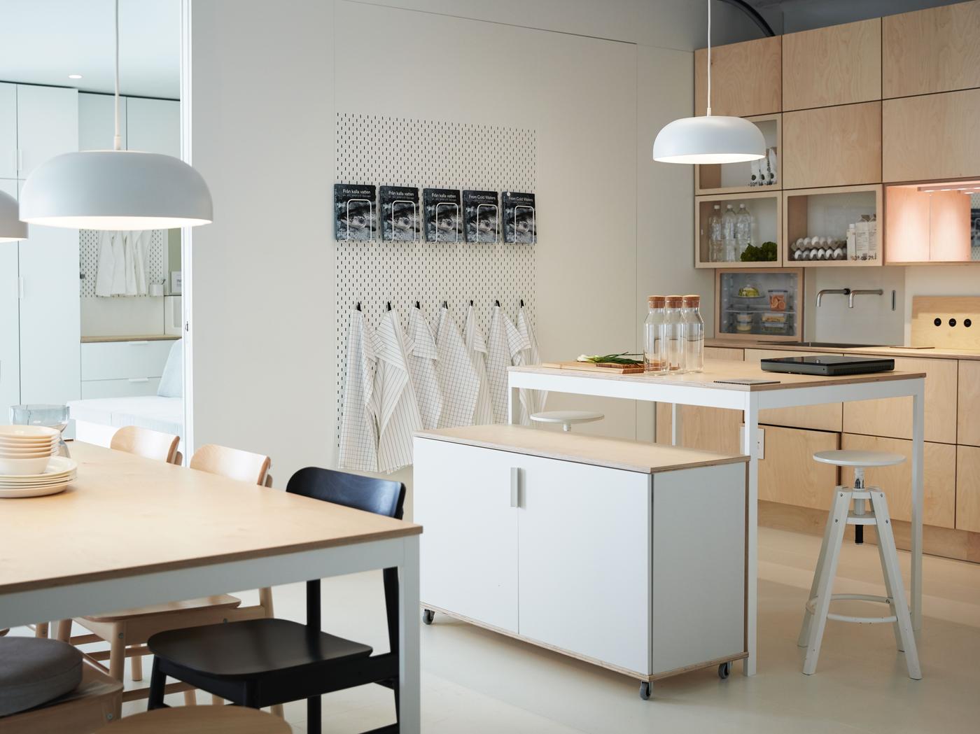 Corner view of a modern kitchen and dining area with light wood fronts and a mix of open and closed overhead cabinets.