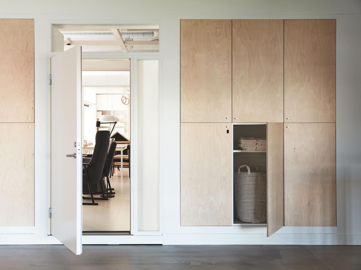 Room with built-in cupboards with light plywood doors.