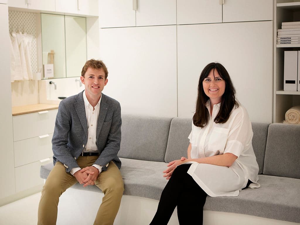 A man and a woman sit on a sofa. They are smiling.