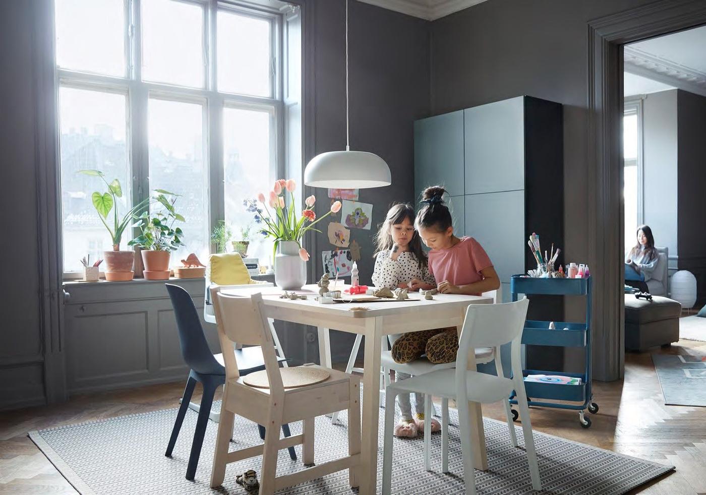 Two children doing crafts at a dining table with a mix of different chairs.