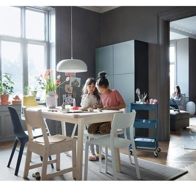 Two children doing crafts at a dining table with a mix of different chairs.