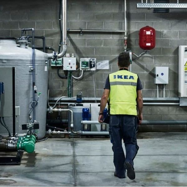 A man on a factory floor, walking away from the camera.