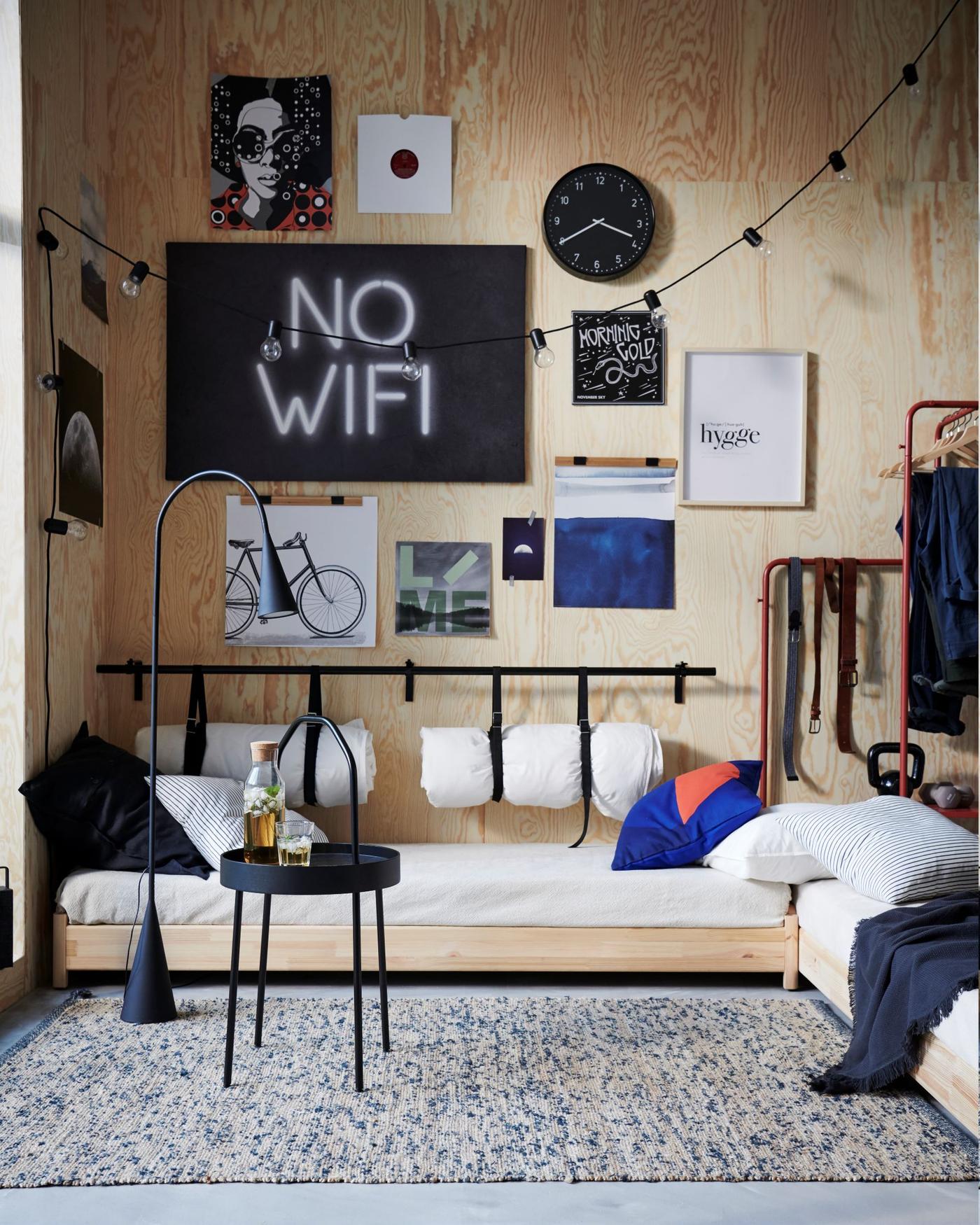 A room with wood walls. There is low seating, a black table and on the wall are posters and a "no wifi" sign.