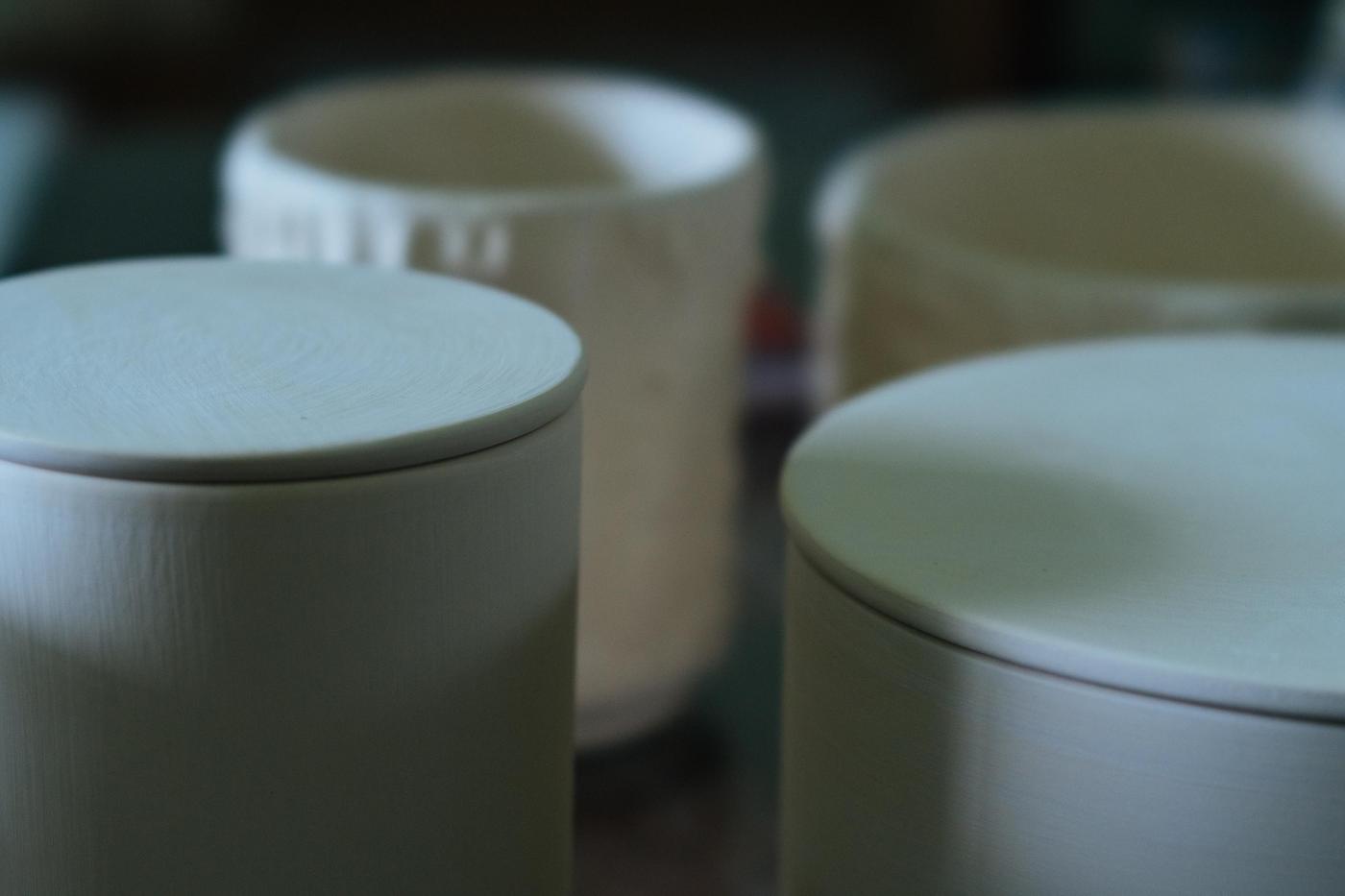 A collection of ceramic candle holders with candles in different sizes.