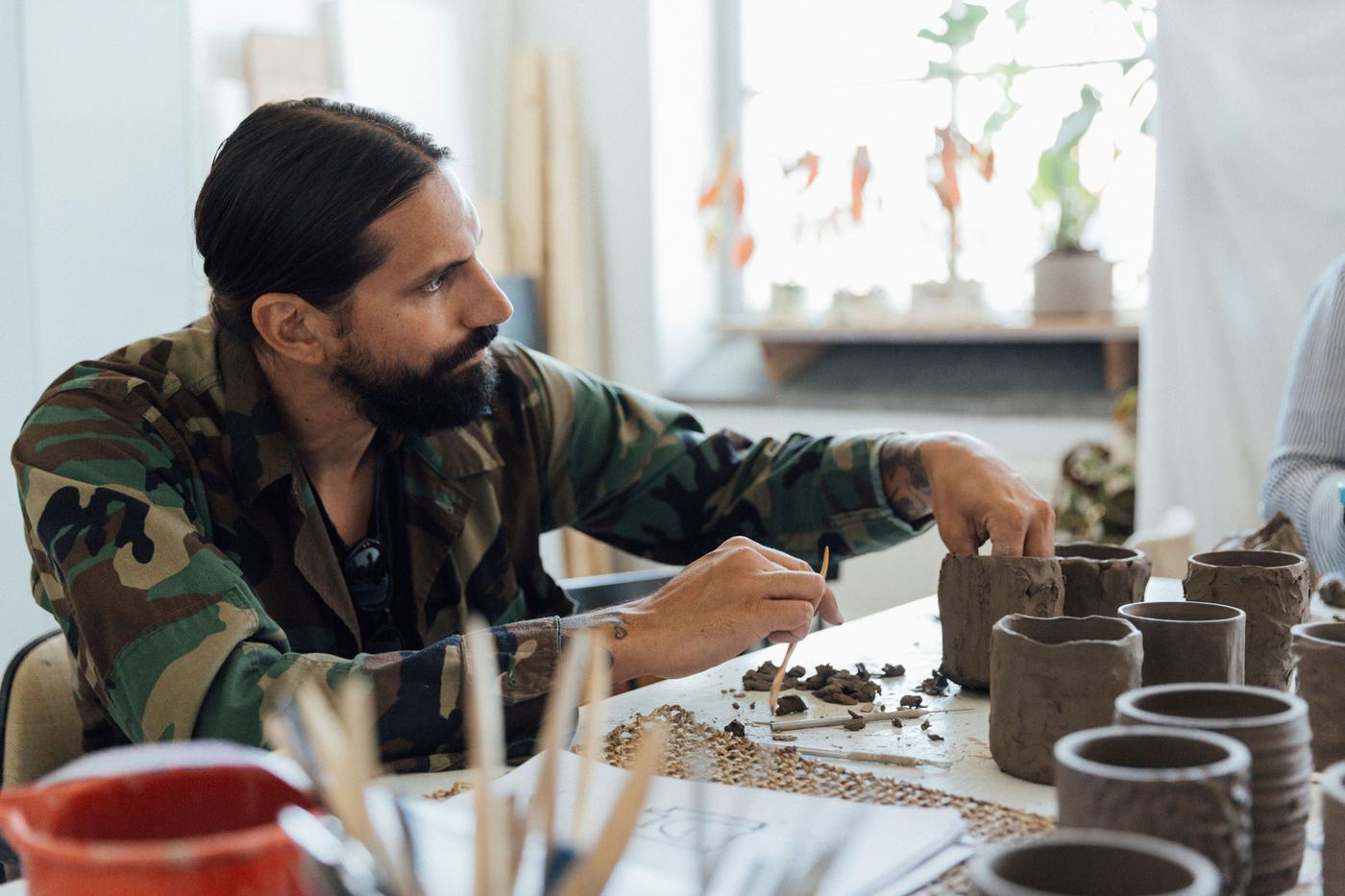 A man moulds a shape with clay.