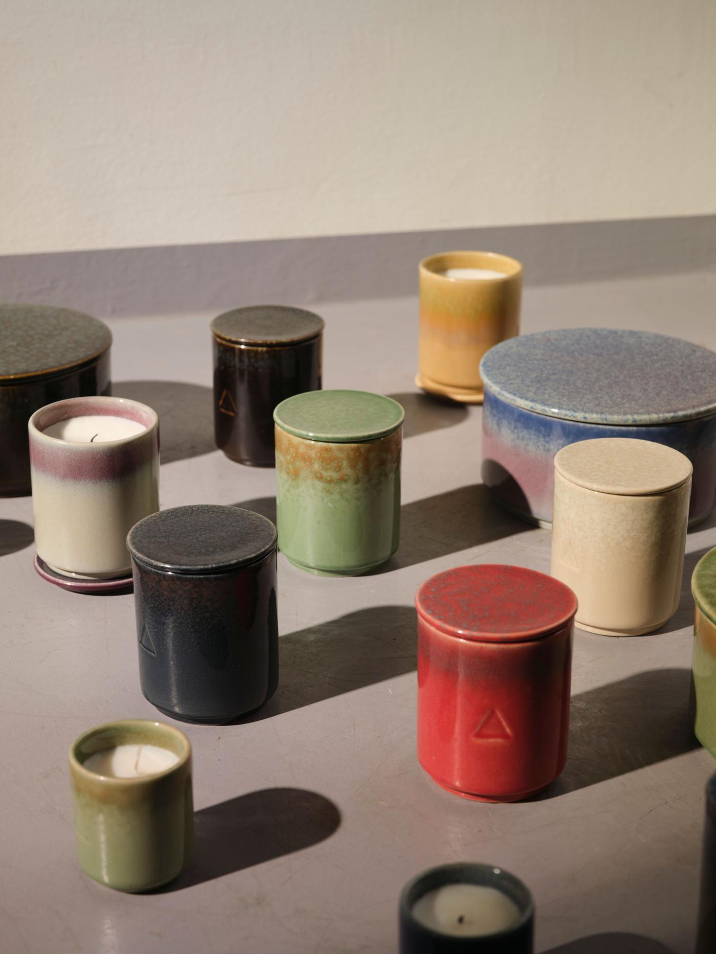 A collection of ceramic candle holders with candles in different sizes and colours.