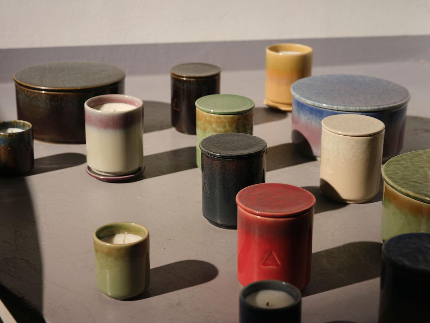 A collection of ceramic candle holders with candles in different sizes and colours.