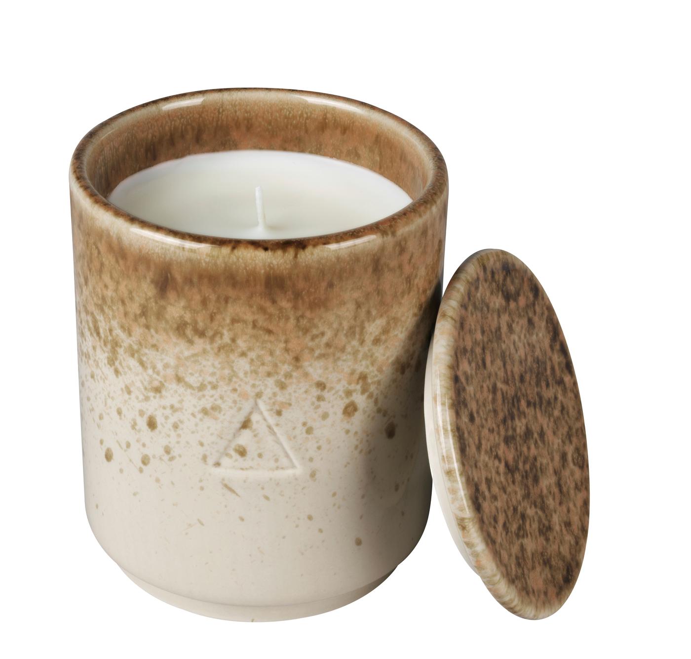 A brown and beige ceramic handle holder with a candle inside and a lid. Against a white background.