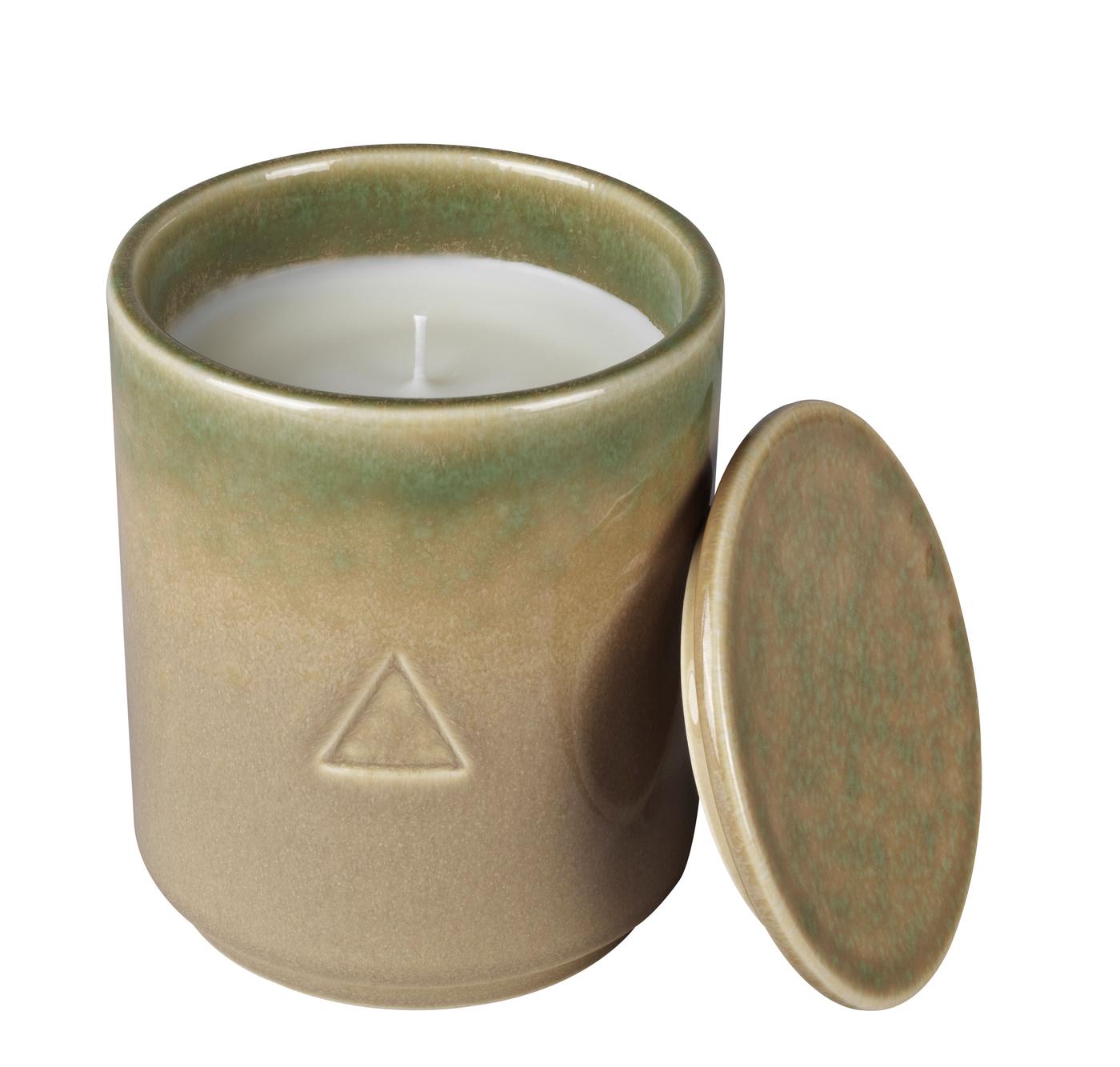 A green and beige ceramic handle holder with a candle inside. Against a white background.