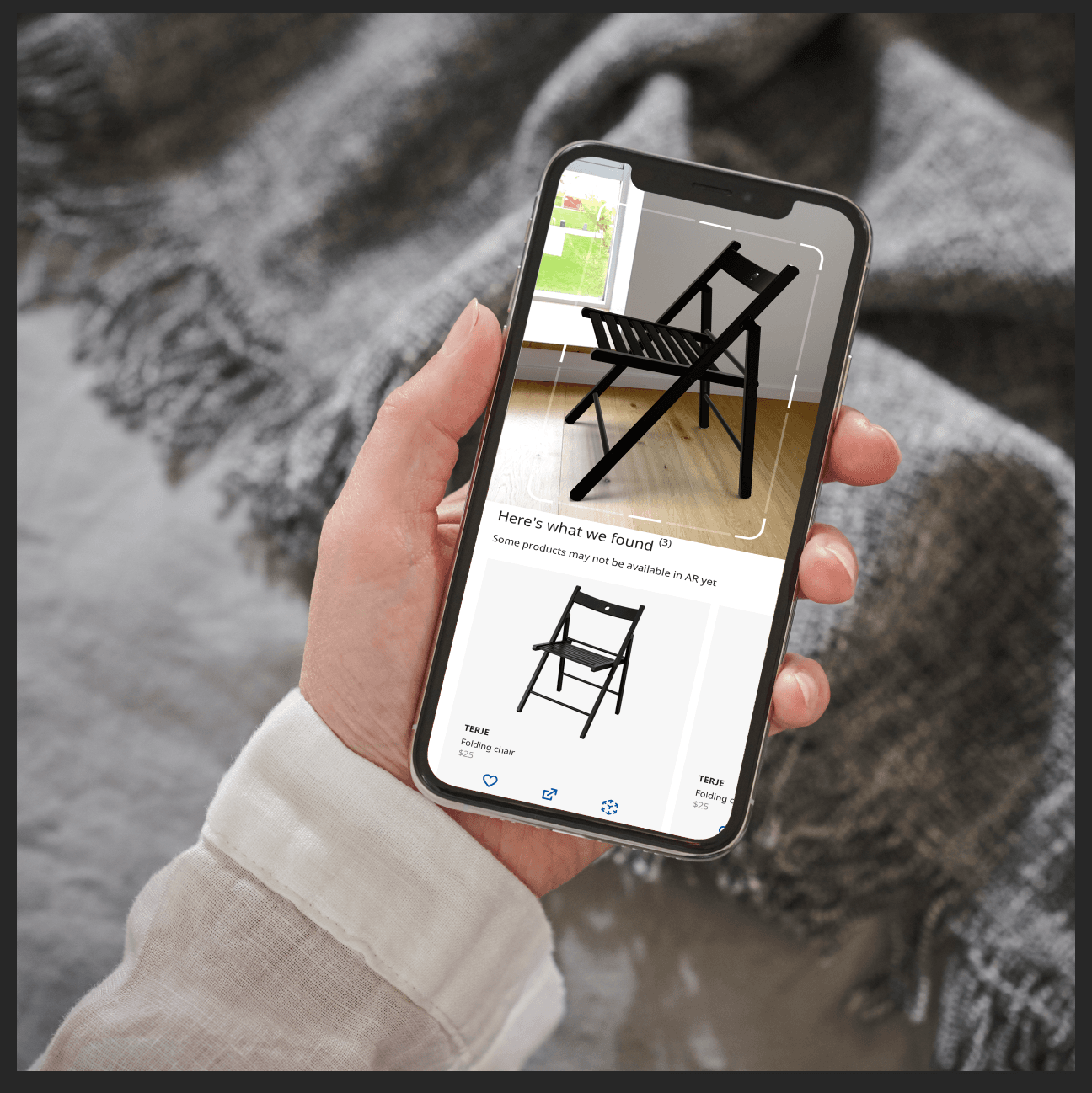 A person holds a smartphone. The screen shows a black chair in a room and the same black chair on a white background.