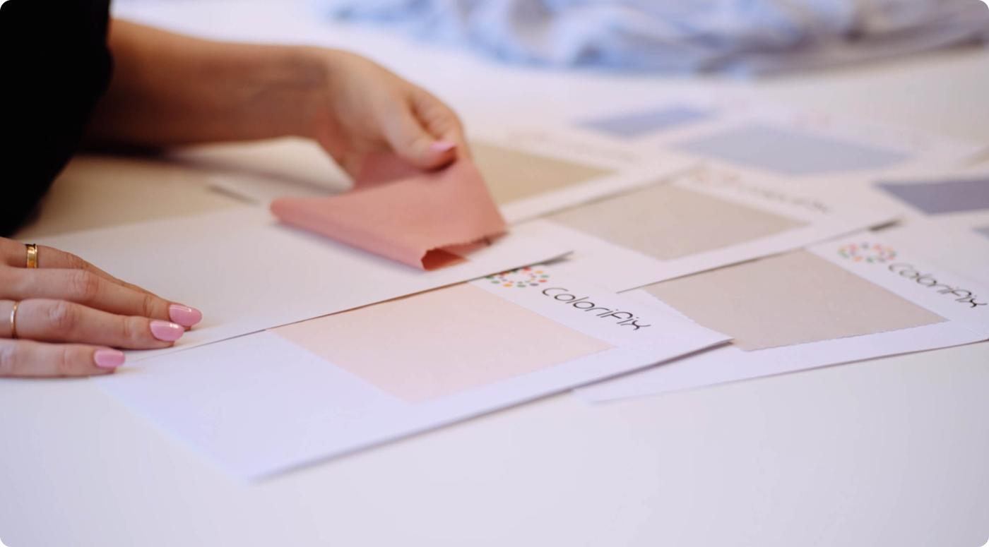 The hands of a person examining swatches of fabric dyed with Colorifix dyes.