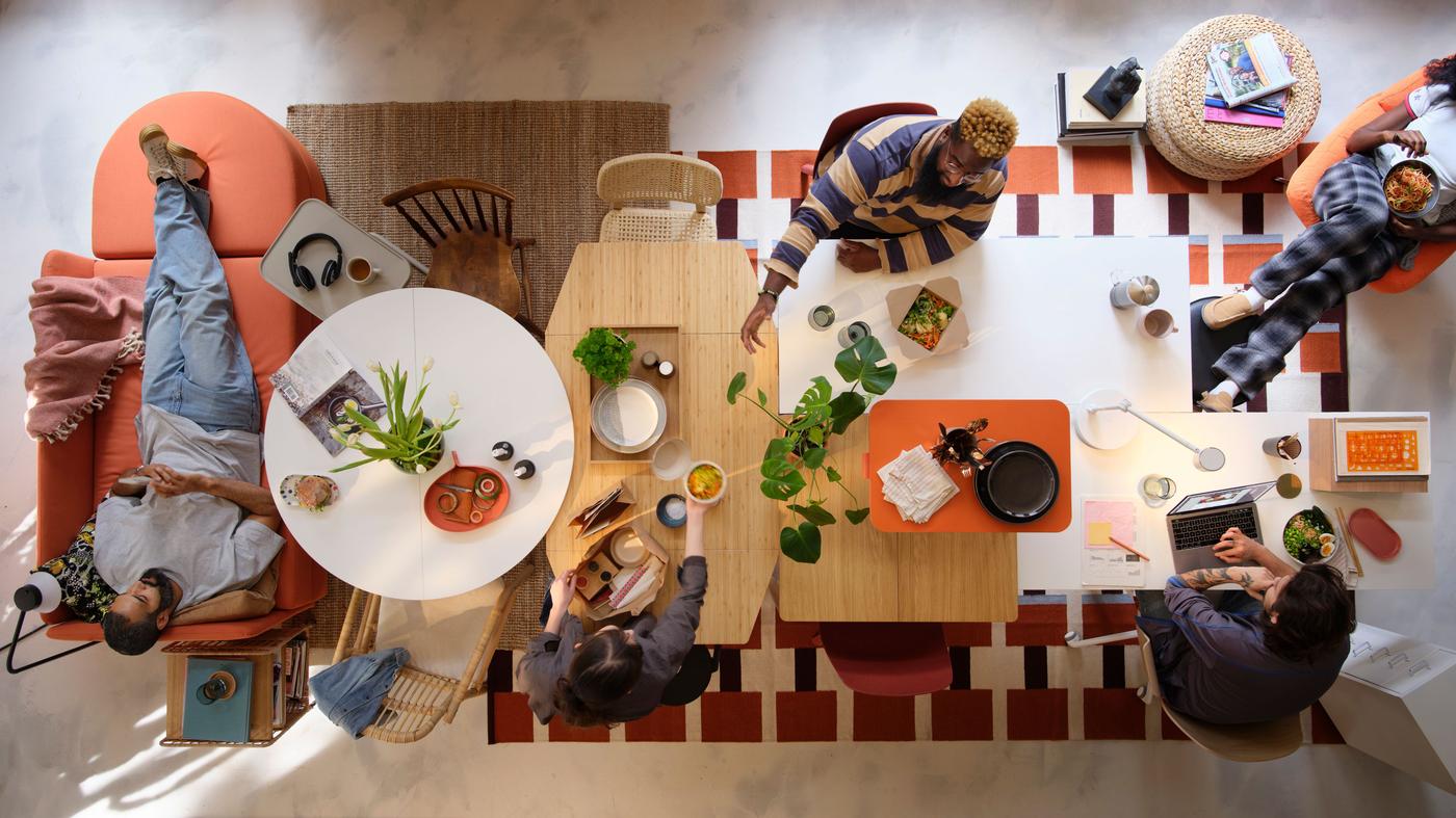An overhead shot of people sitting around several different tables pushed together with mismatched chairs.