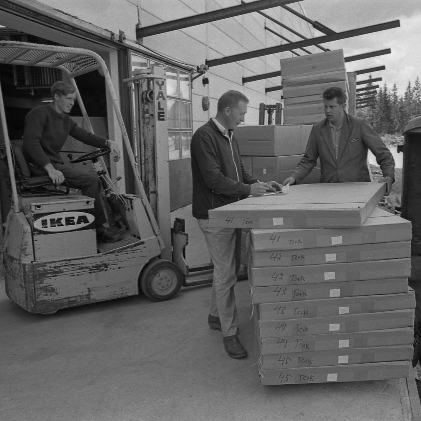 A potograph from the mid-sixties of two men unloading boxes next to a forklift at the quay at DC Älmhult.