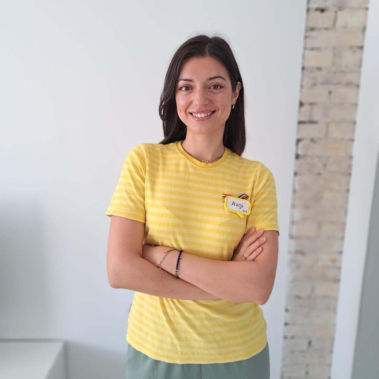 Avgi smiles at the camera, with crossed arms.