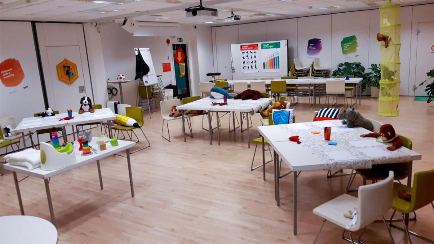 A schoolroom with soft toys sitting at the desks.