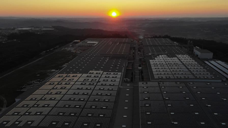 Solar panels on a lage rooftop with a sunset on the horizon in the distance.