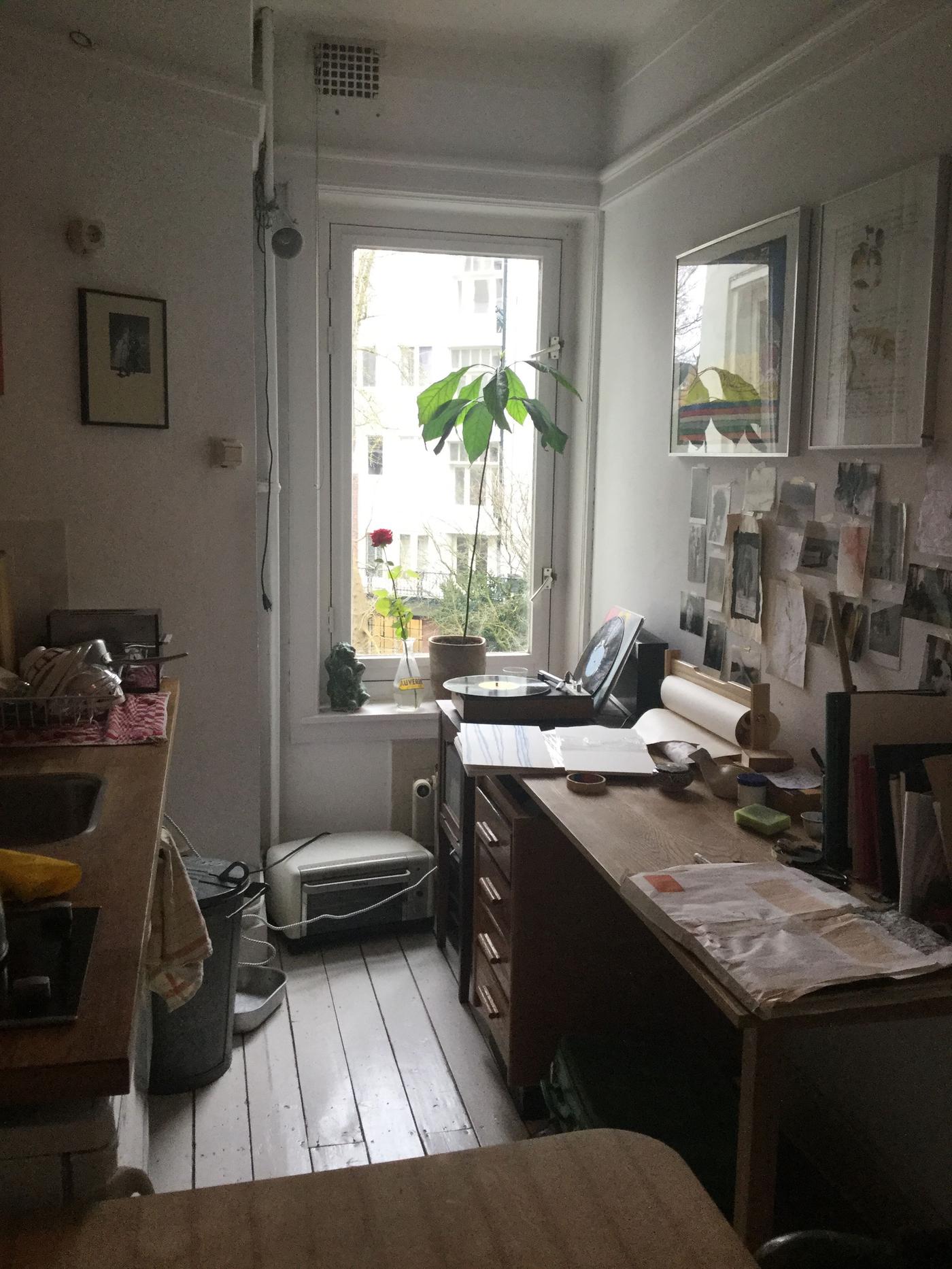 A workspace in a small room with a window and a plant.