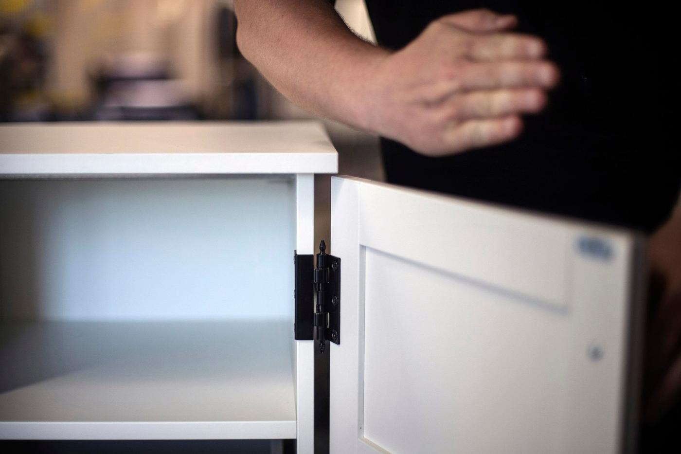 A hand pointing out from a cabinet of drawers.