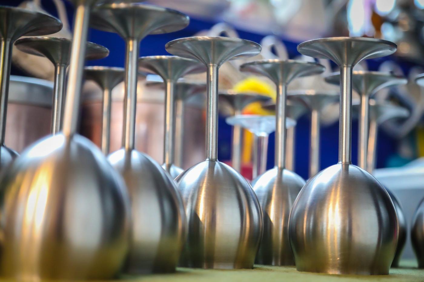 A number of wine glasses in stainless steel standing upside down.
