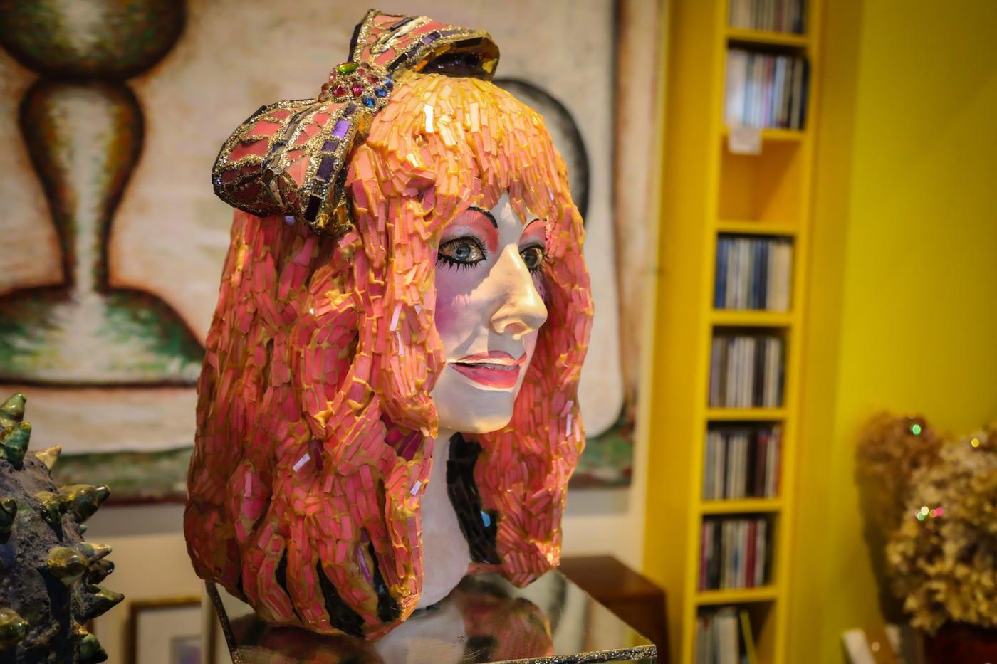 A statue of a woman with bright makeup, ginger hair and a big bow on her head.