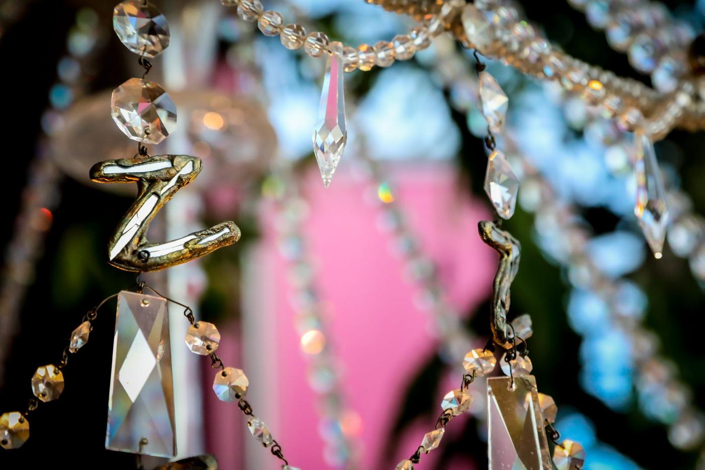 A detail of a crystal chandelier with irregular pieces and letters.