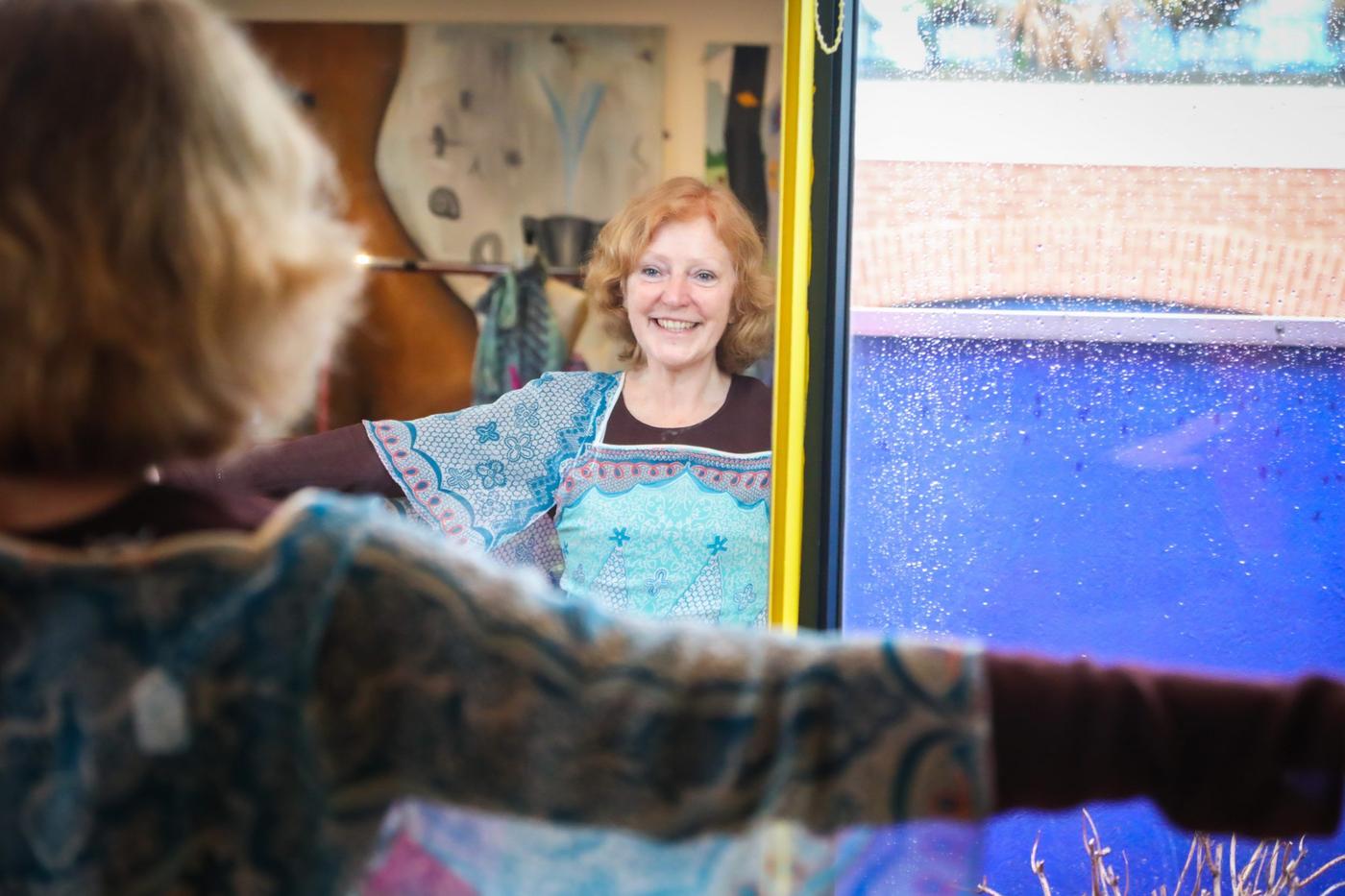 A happy woman looking at herself in a mirror while trying on a dress.
