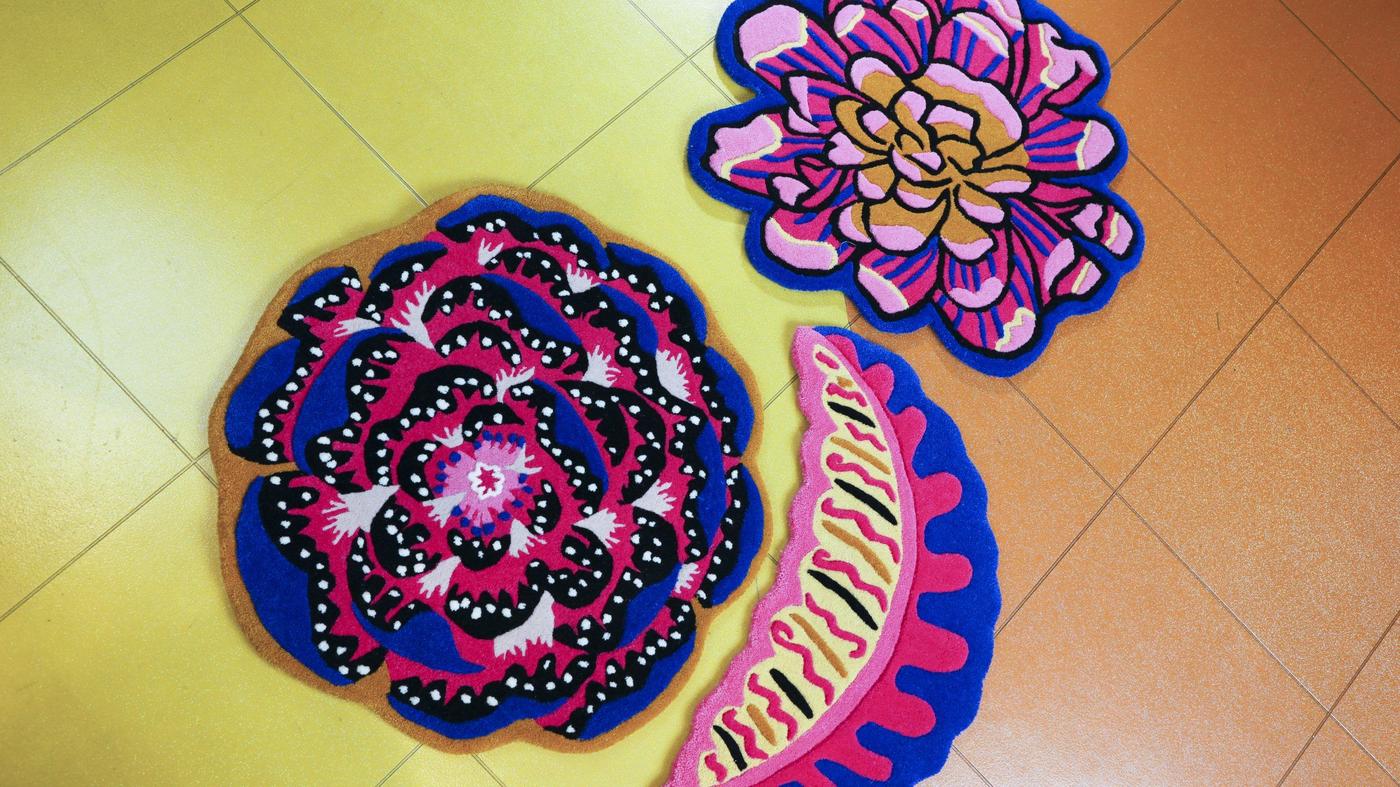 Colourful cut-out prints of flowers on a surface tiled in yellow and orange.