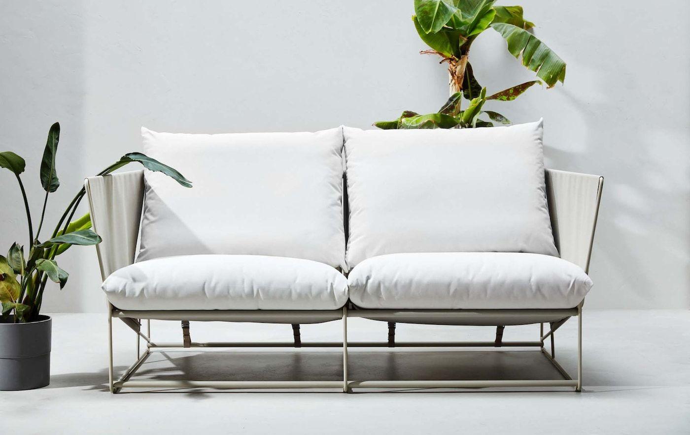 A HAVSTEN 2-seat sofa in a white studio setting surrounded by tropical plants.