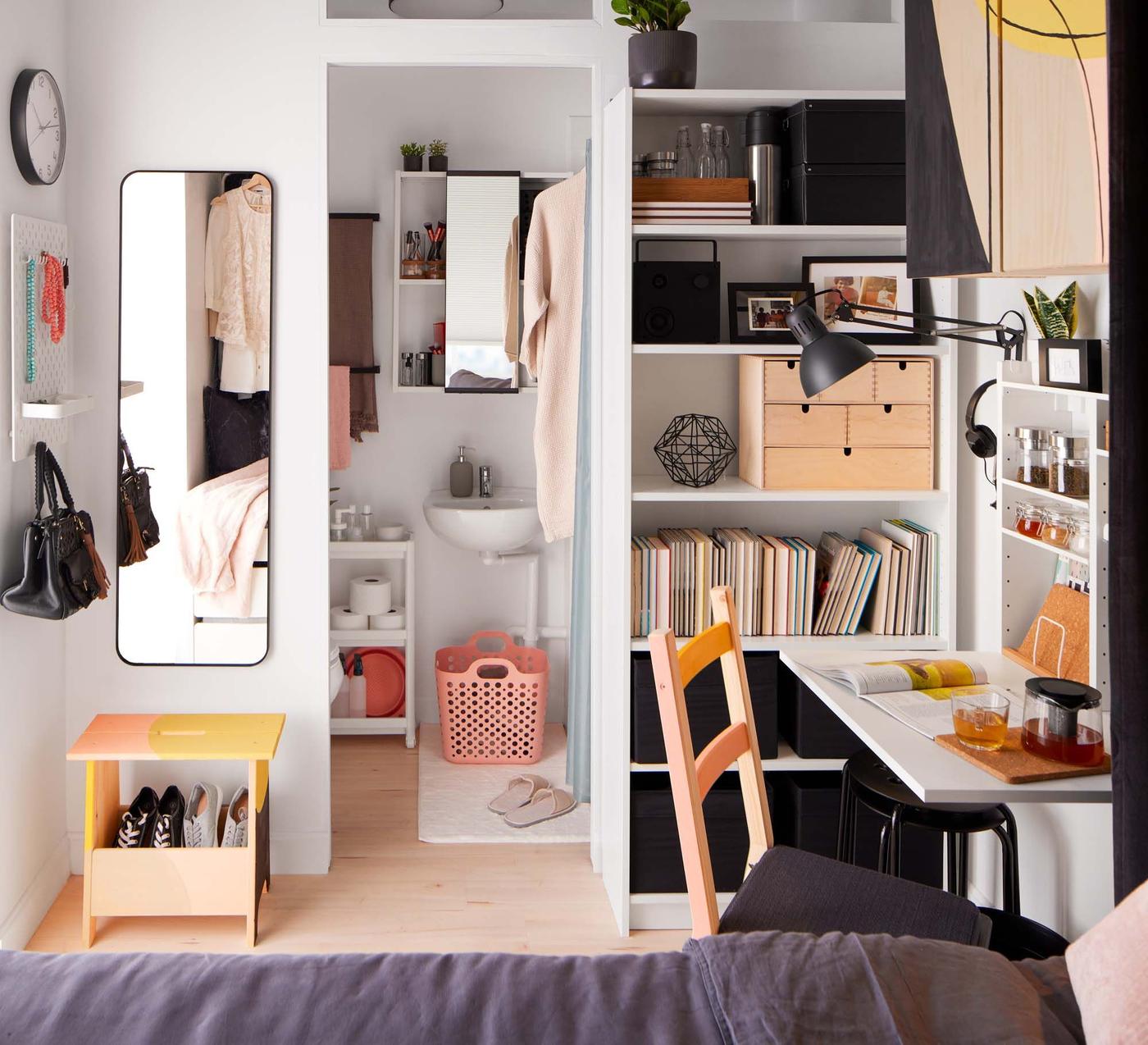 View of a tiny apartment, looking from the sleeping area across the living space and into the bathroom.