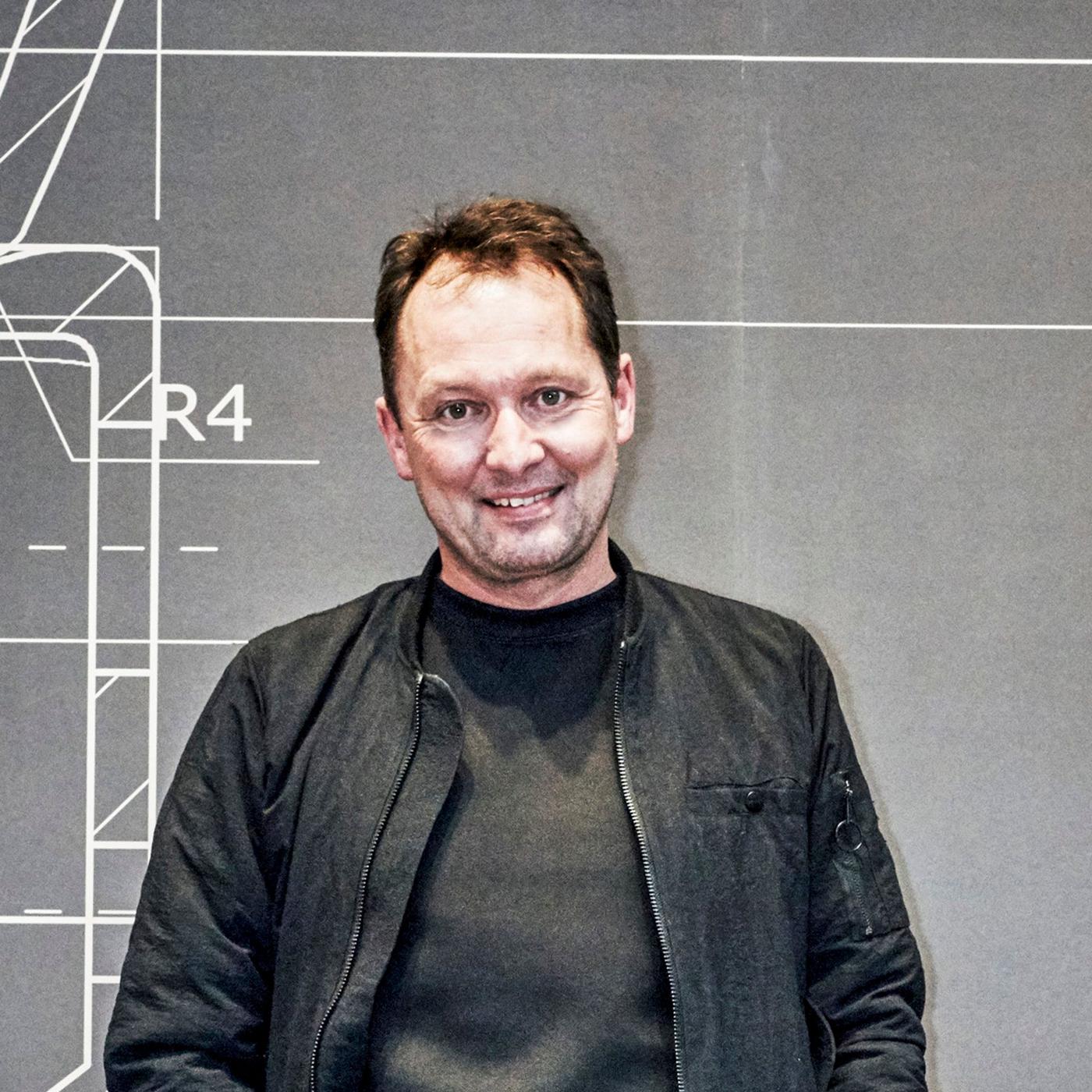 A portrait of a man in a black shirt and jacket.