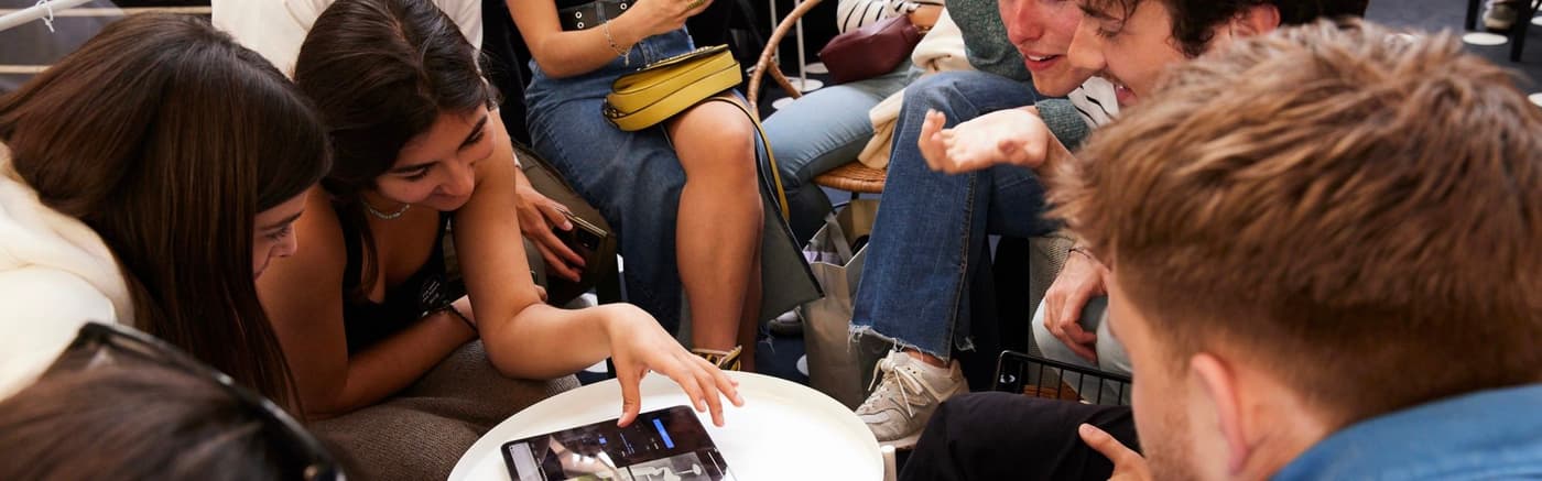 A group of students in a workshop, sitting round a table and an Ipad.