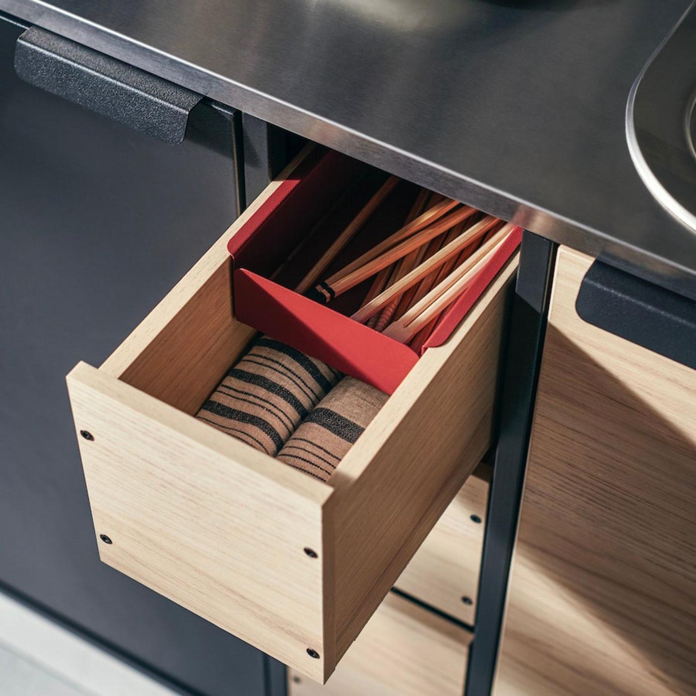 A kitchen drawer with towels and chopsticks. 