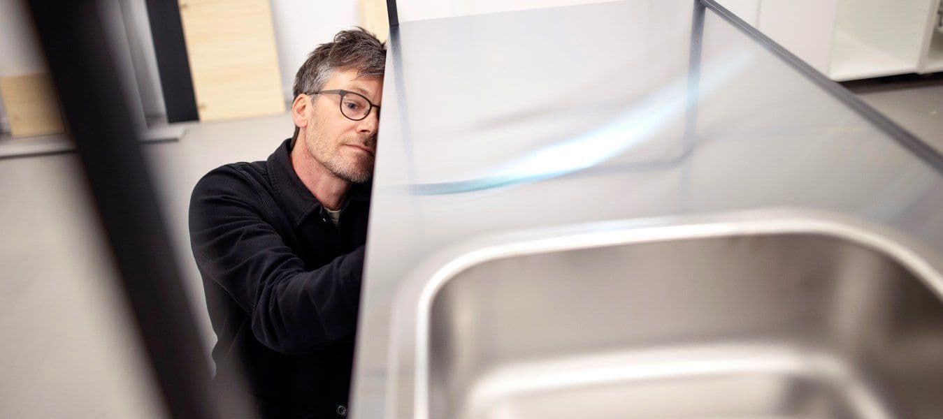 A man in a black shirt assembles a sink.