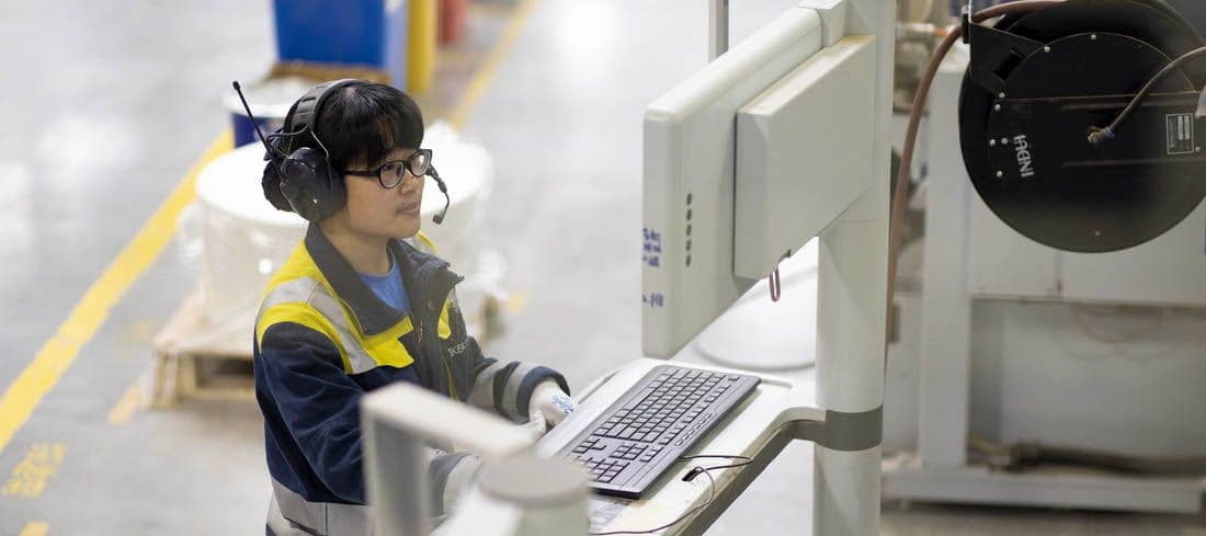 A co-worker in an industrial facility operates a computer.